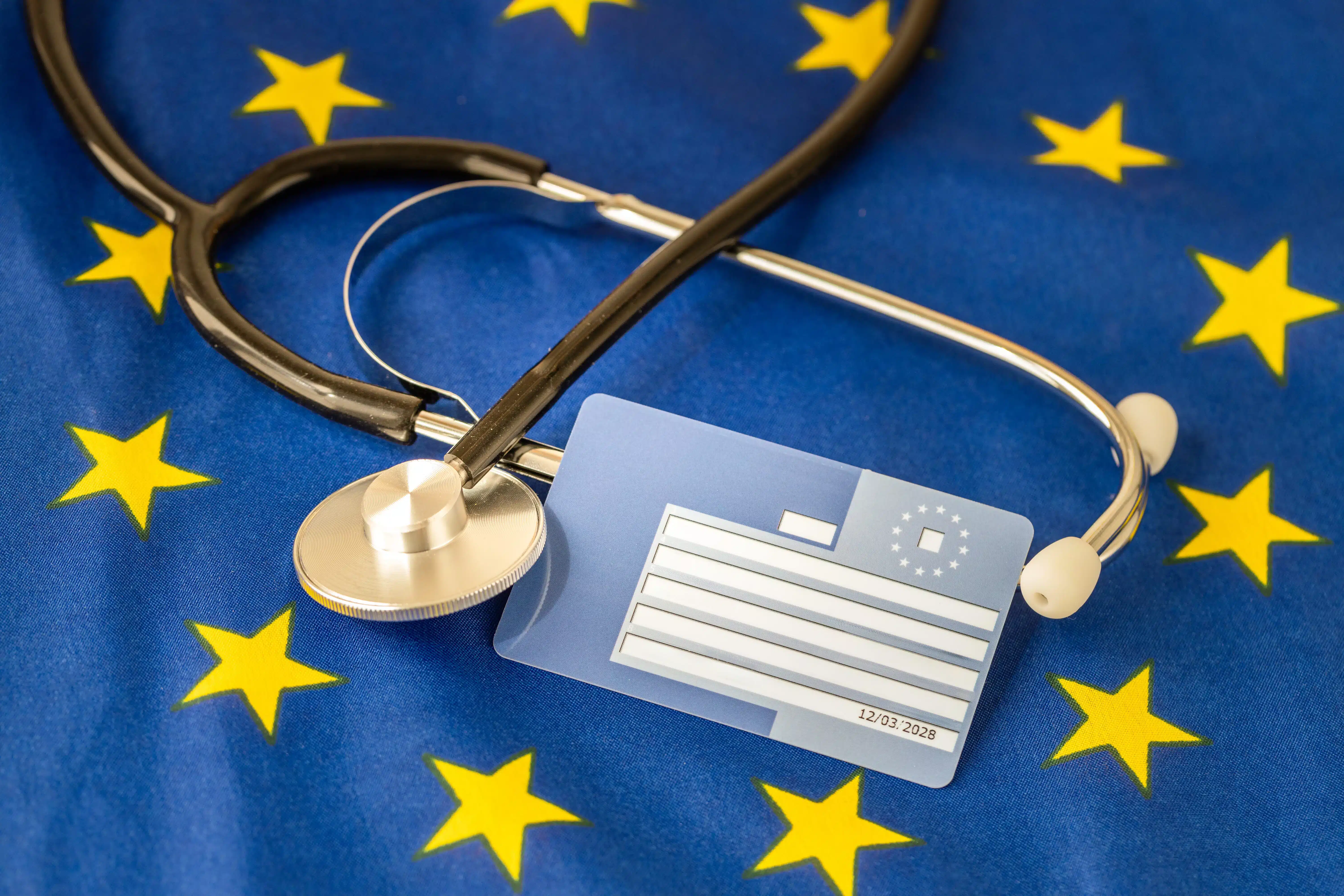 Carte européenne d'assurance maladie avec un stéthoscope posé sur un drapeau de l'UE